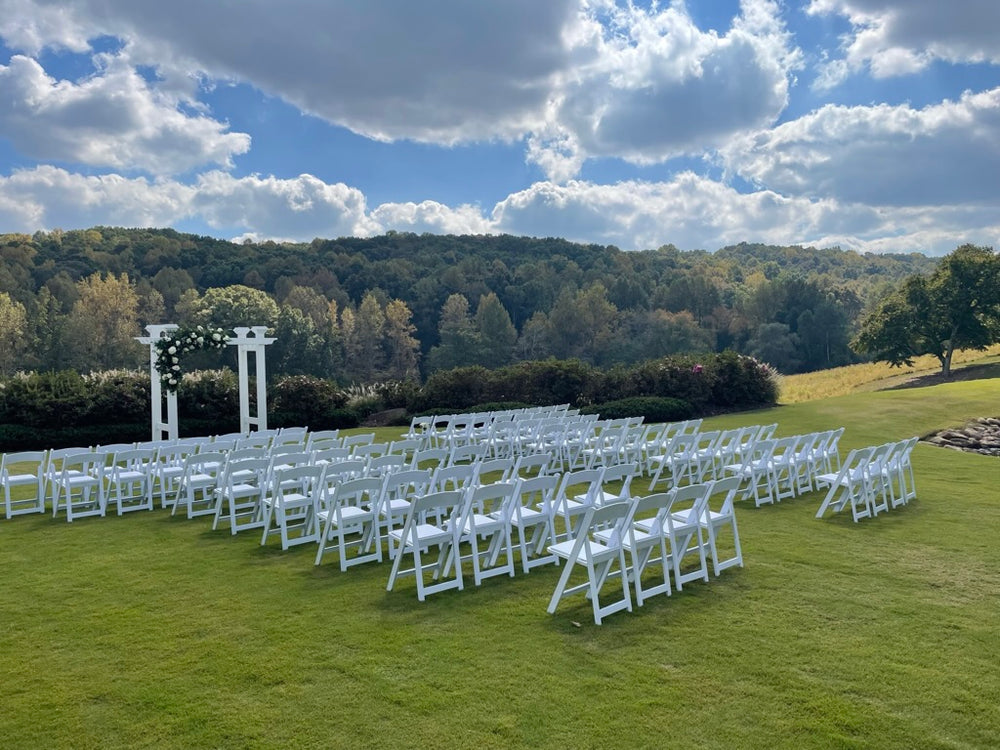 Wedding set up with floral arch and white folding chairs